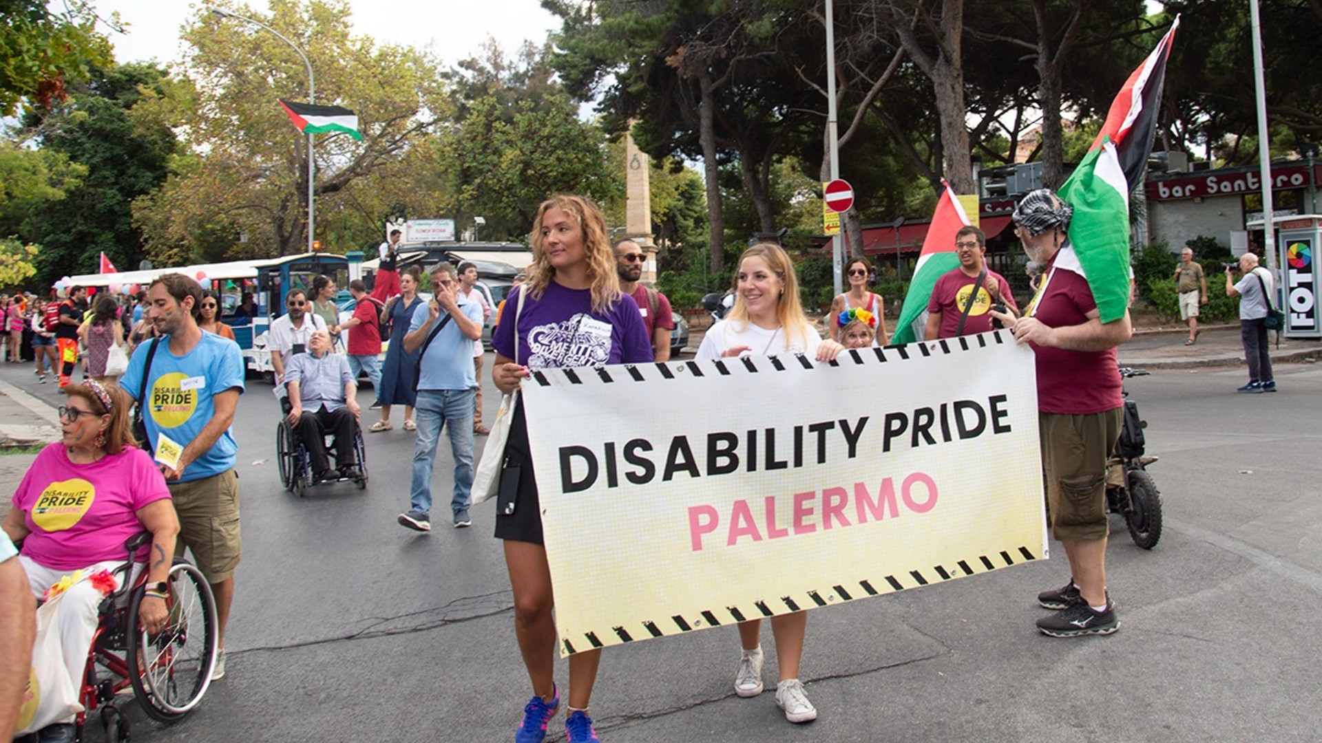 Due persone tengono la banner 'disability pride palermo' in un corteggio.