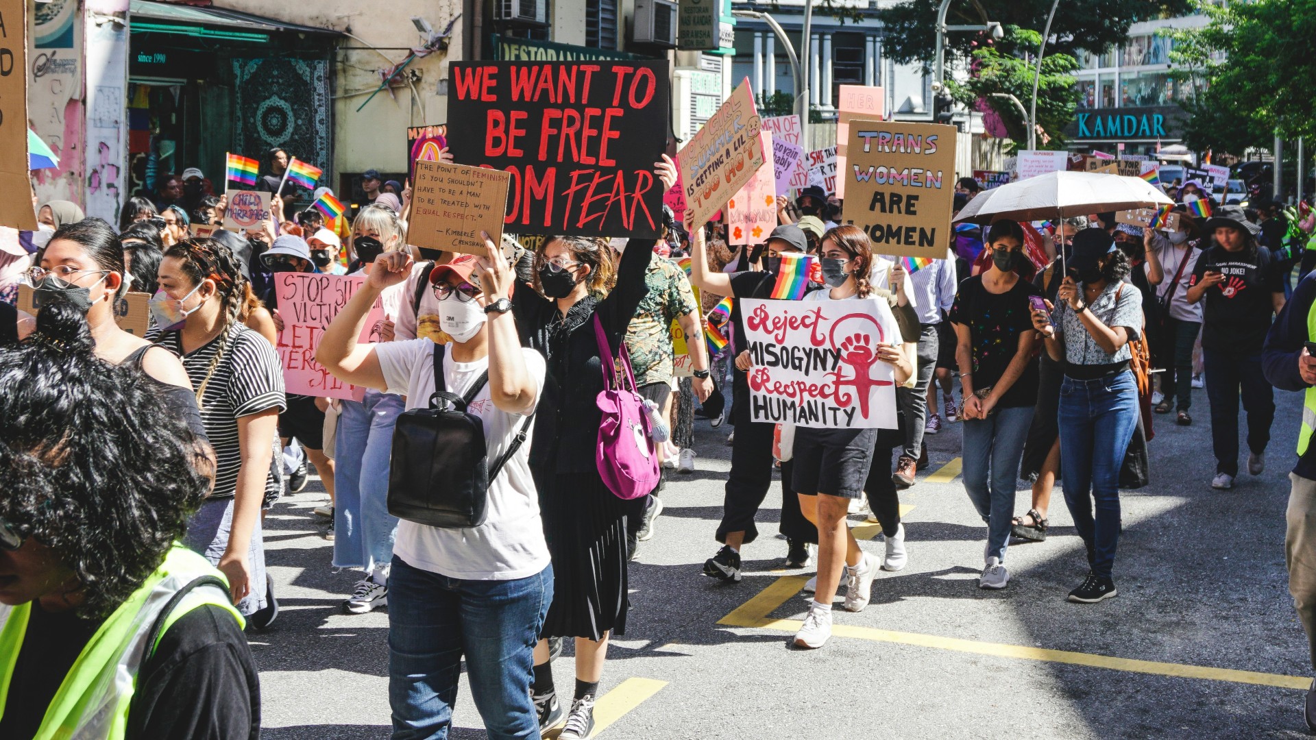 People at a protest with signs 'we want to be free from fear' and 'reject misogyny respect humanity'.